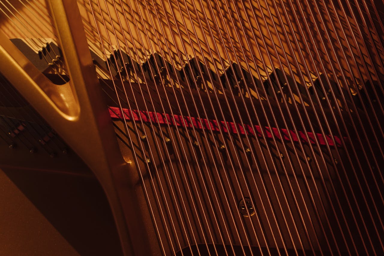 Detailed view of grand piano strings showing intricate design in warm lighting.